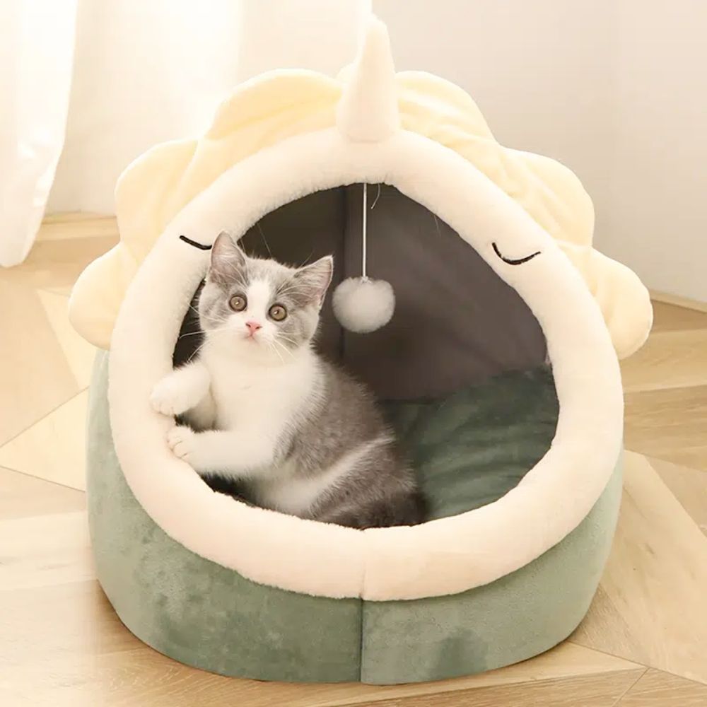 Gato cinza e branco sentado dentro do Adorable Dinosaur Pet House with Toy, uma casa de pelúcia em forma de dinossauro confortável e acolhedora, perfeita para relaxar.