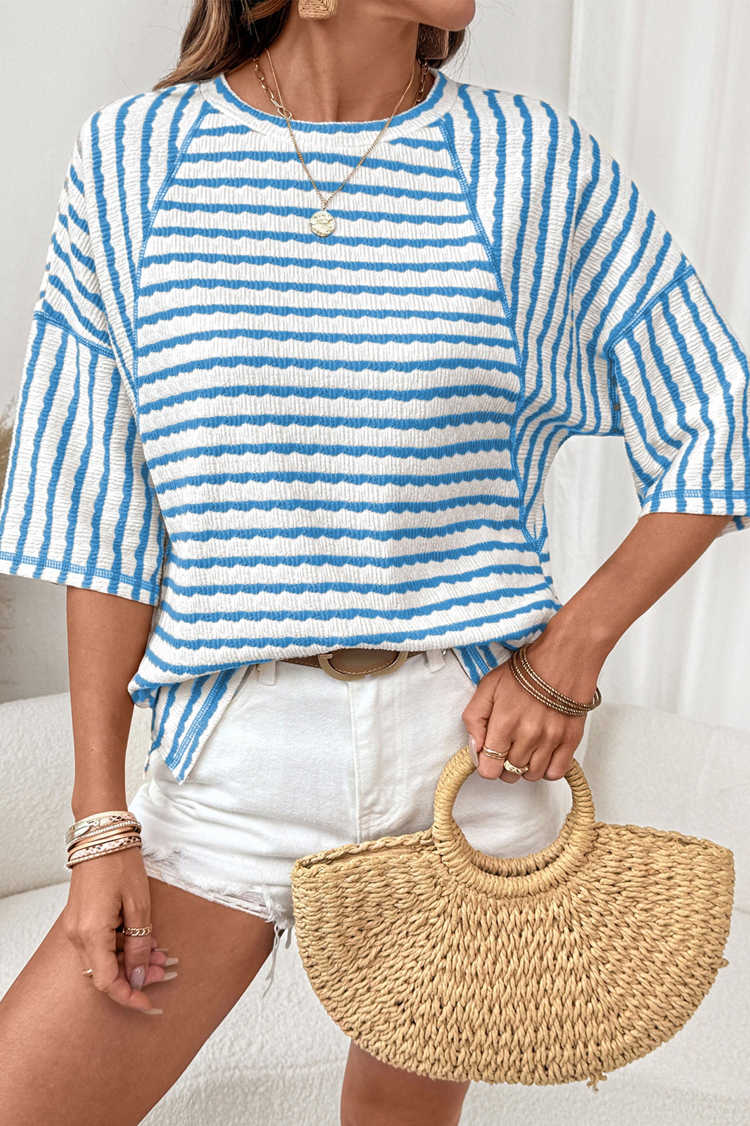 Mulher vestindo Apricot Stripe Textured Knit Split Hem Half Sleeve Loose Top listrado azul e branco, com acessórios dourados e bolsa de palha, promovendo suplementos premium naturais para energia, vitalidade e saúde cognitiva.