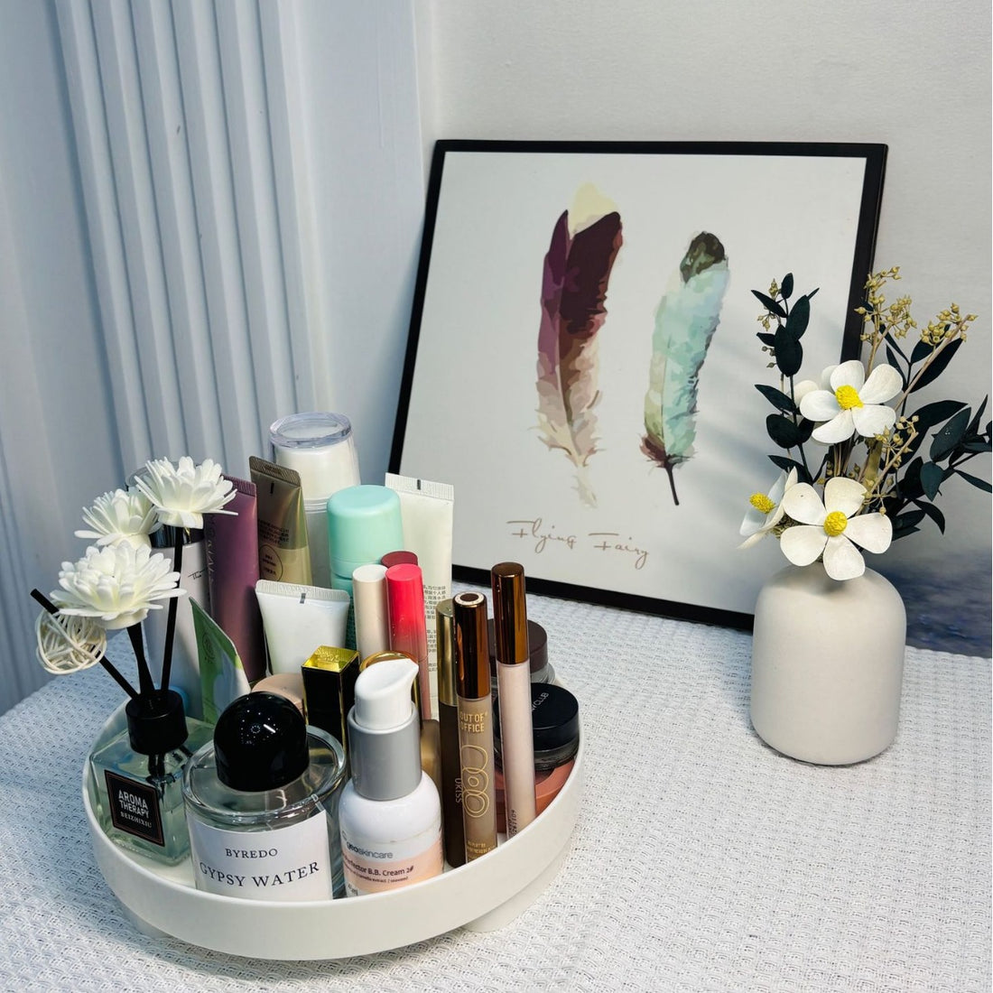 Organização elegante com ins desktop cosmetics storage box tray entrance ornaments storage tray contendo cremes, perfume e itens de beleza, complementada por flores decorativas e quadro com penas. Suplementos premium naturais para energia, vitalidade e saúde cognitiva, desenvolvidos para o mercado português.