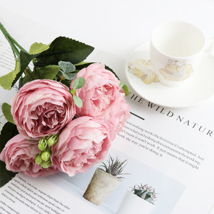 Buquê delicado de flores artificiais rosa claro composto por 5 unidades, acompanhado de uma xícara branca com detalhes dourados e um livro aberto, ideal para decoração. 5 Small Peonies Korean Small Bouquets 5 Philips Rose Simulation Flowers Household Wedding Rose Bouquets suplementos premium naturais para energia, vitalidade e saúde cognitiva, desenvolvidos para o mercado português.