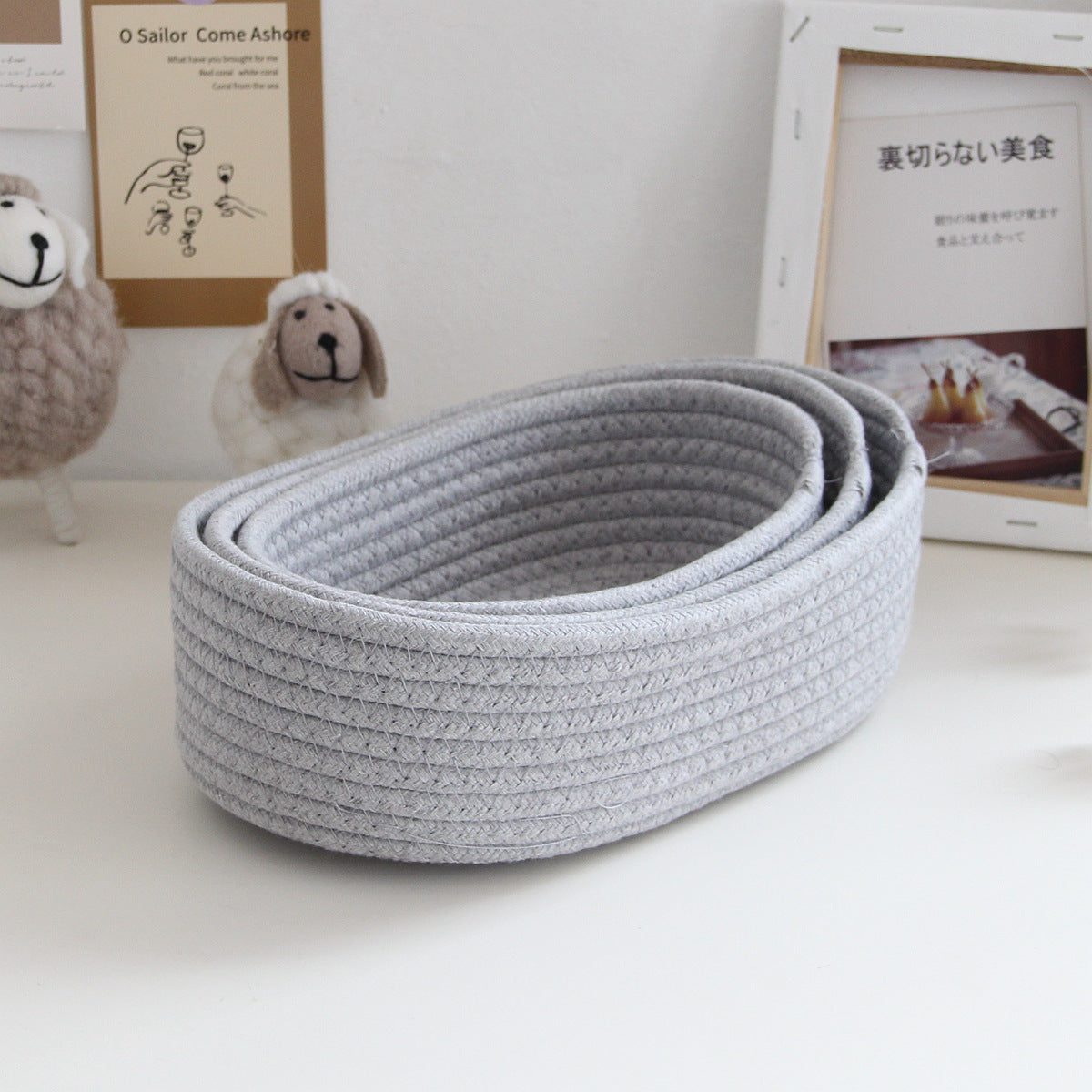 Storage box desktop miscellaneous items storage basket cosmetics snacks hallway hand woven cotton thread storage basket cinza claro colocado sobre mesa branca com decoração de ovelhas de pelúcia ao fundo, ideal para organizar suplementos premium naturais para energia, vitalidade e saúde cognitiva.