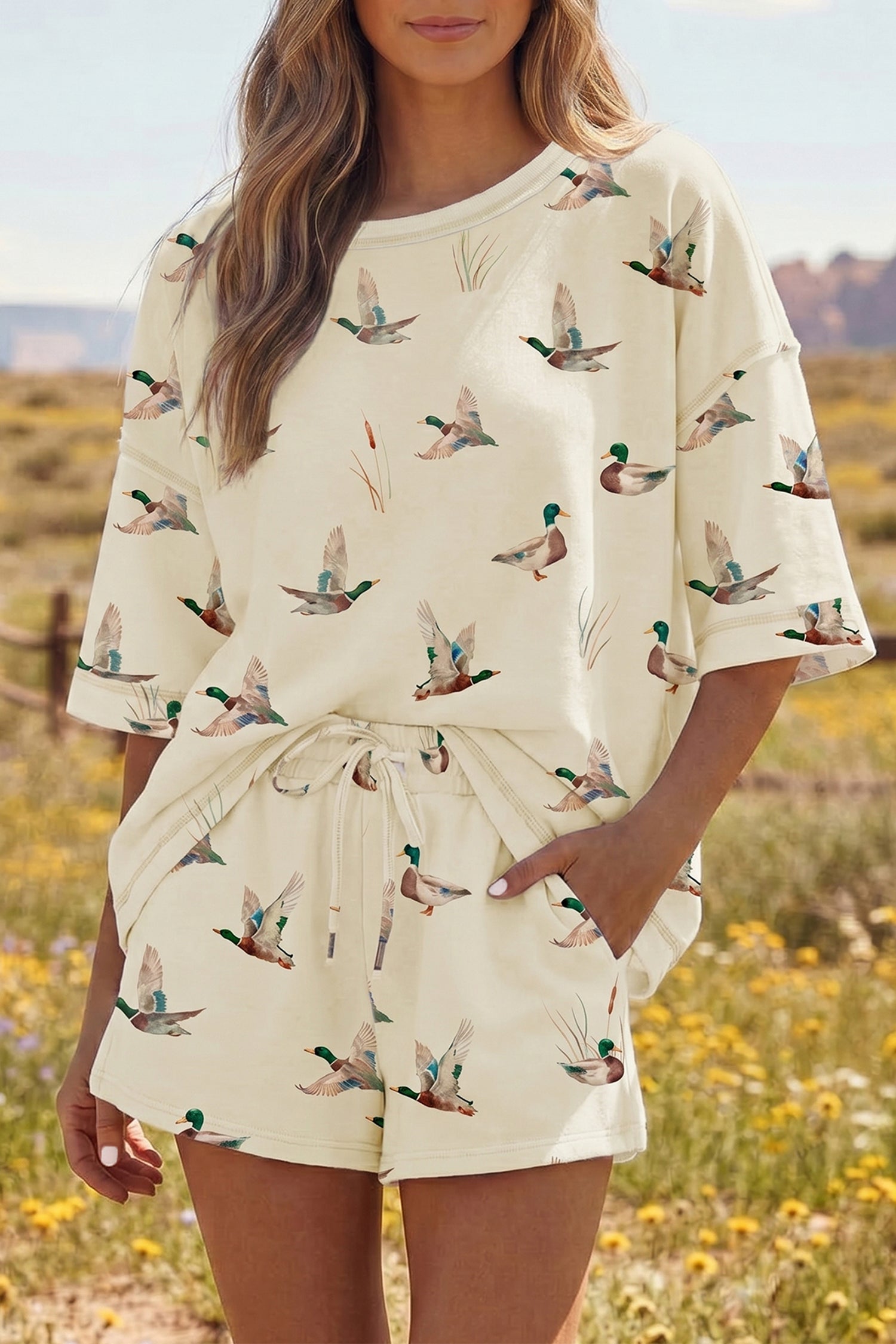 Mulher ao ar livre vestindo Beige Mallard Duck Print Oversized Tee Drawstring Short Set, conjunto confortável e casual, ideal para relaxar com estilo natural e descontraído.