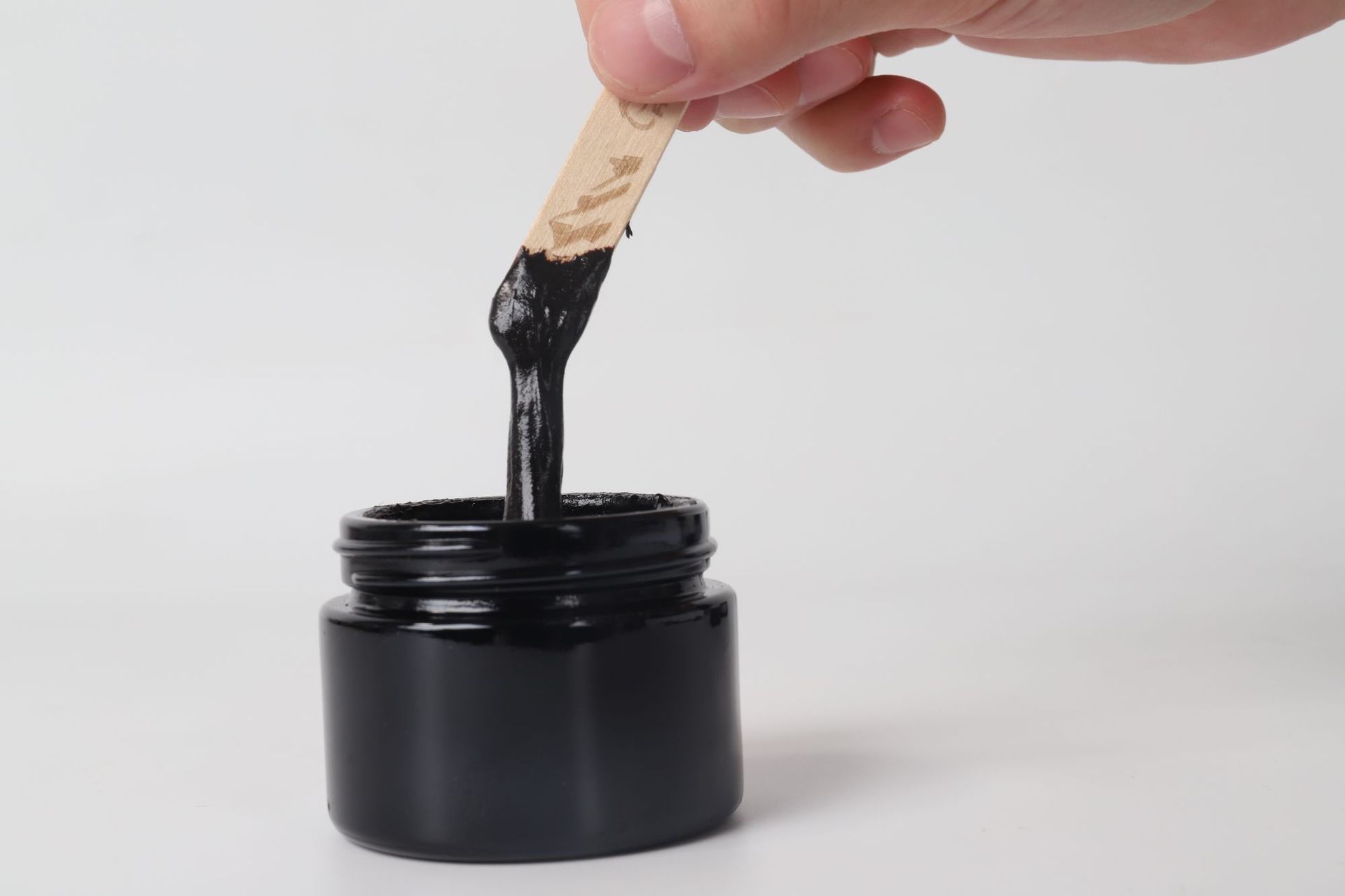 Pure Himalayan Shilajit SoftResin em pote preto, mostrando textura resinosa preta sendo retirada com espátula, suplemento premium natural para energia, vitalidade e saúde cognitiva.