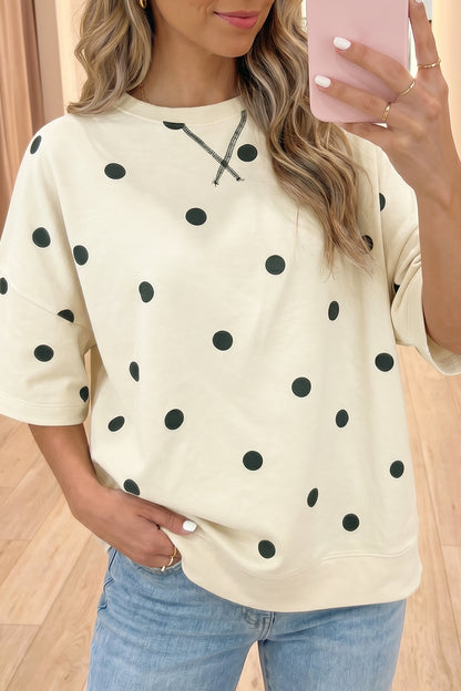 Pessoa a tirar selfie com smartphone, vestindo Yellow Polka Dot Print Crossed Seam Detail Oversize Tee, camiseta oversize creme com bolinhas pretas, cabelo ondulado e acessórios delicados.