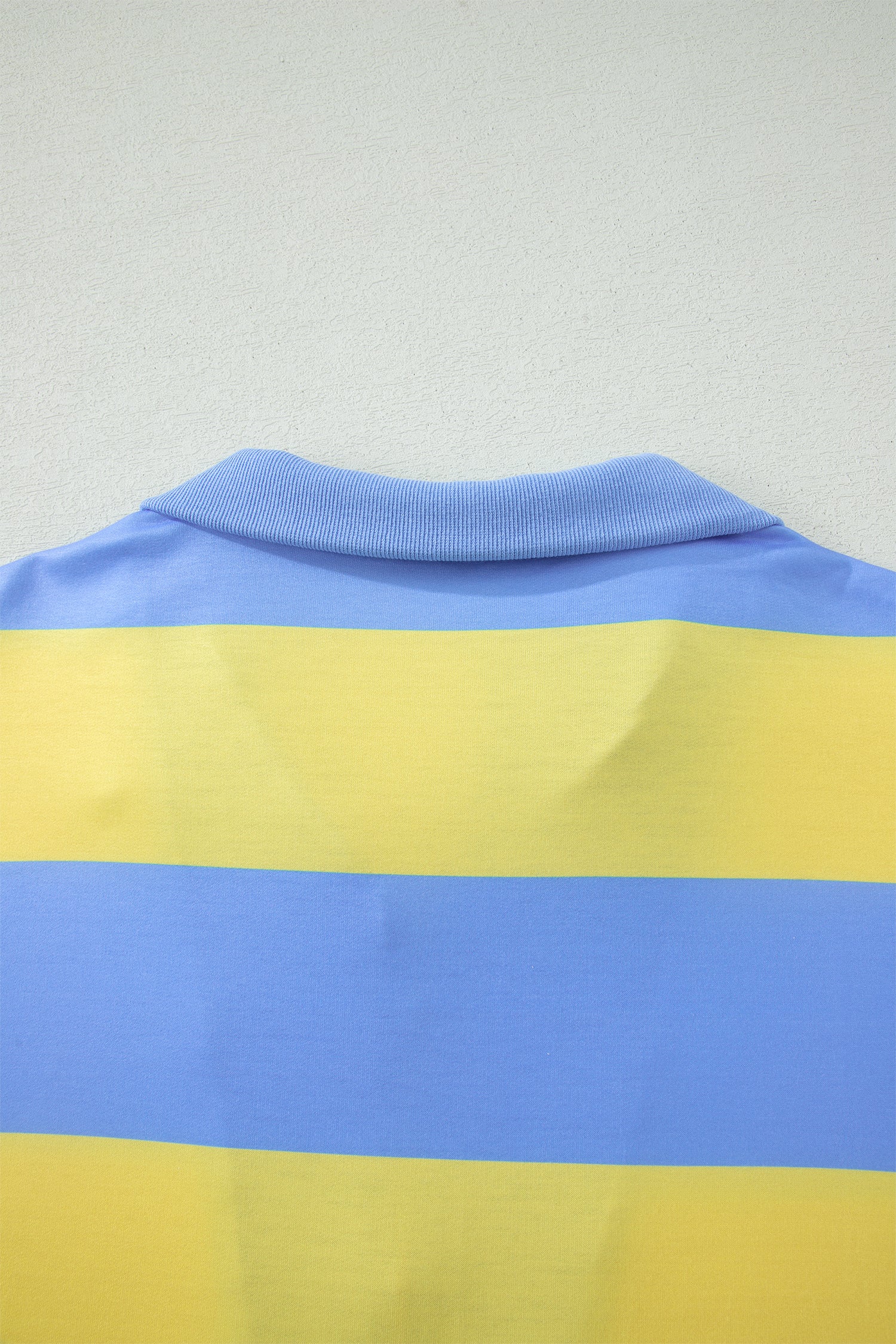 Imagem da parte traseira de uma peça de vestuário em tons azul e amarelo, destacando detalhes da gola, relacionada ao Pink Seam Detail Half Zip Tee Casual Shorts 2pcs Set, ideal para complementar o estilo casual com conforto, promovendo bem-estar natural e energia.