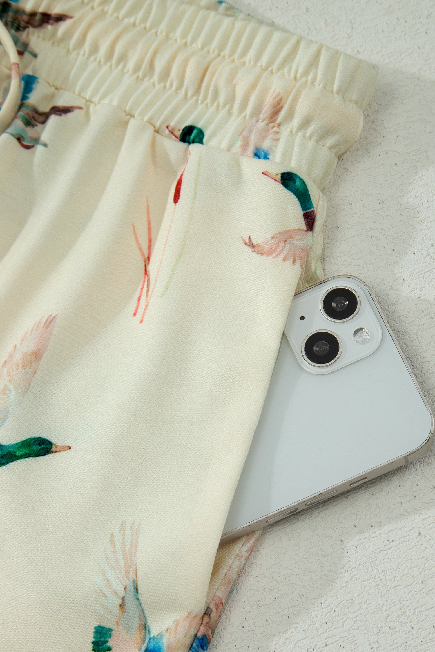 Detalhe do beige mallard duck print oversized tee drawstring short set com bolso, mostrando tecido macio e estampa de pato em ambiente minimalista.