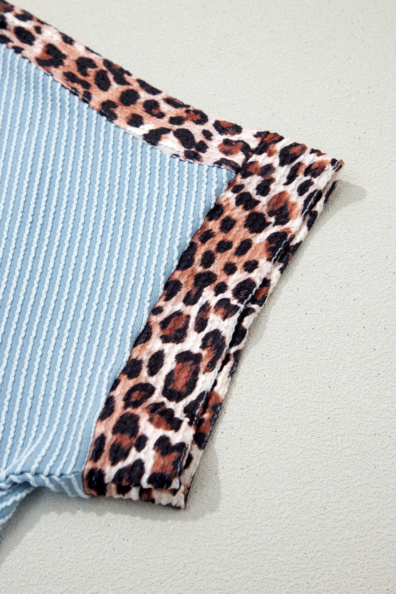 Detalhe em tecido canelado cinza claro com acabamento estampado padrão Light Grey Leopard Trim Twist Ribbed Short Set, representando a elegância suave e natural.