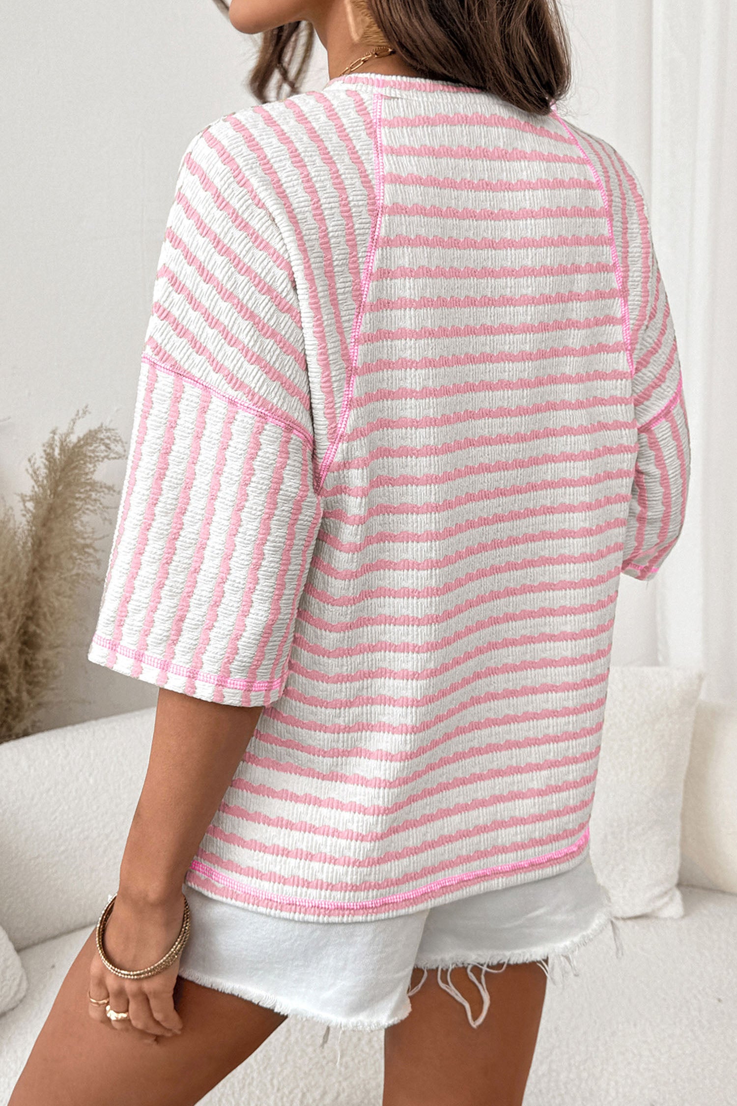 Pessoa vista de costas vestindo Apricot Stripe Textured Knit Split Hem Half Sleeve Loose Top com padrão listrado rosa e branco, em ambiente claro e casual, suplementos premium naturais para energia, vitalidade e saúde cognitiva.