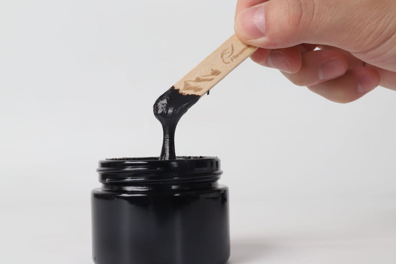 Cerca de um frasco preto com Pure Himalayan Shilajit SoftResin sendo retirado com uma espátula de madeira, suplemento premium natural para energia, vitalidade e saúde cognitiva.