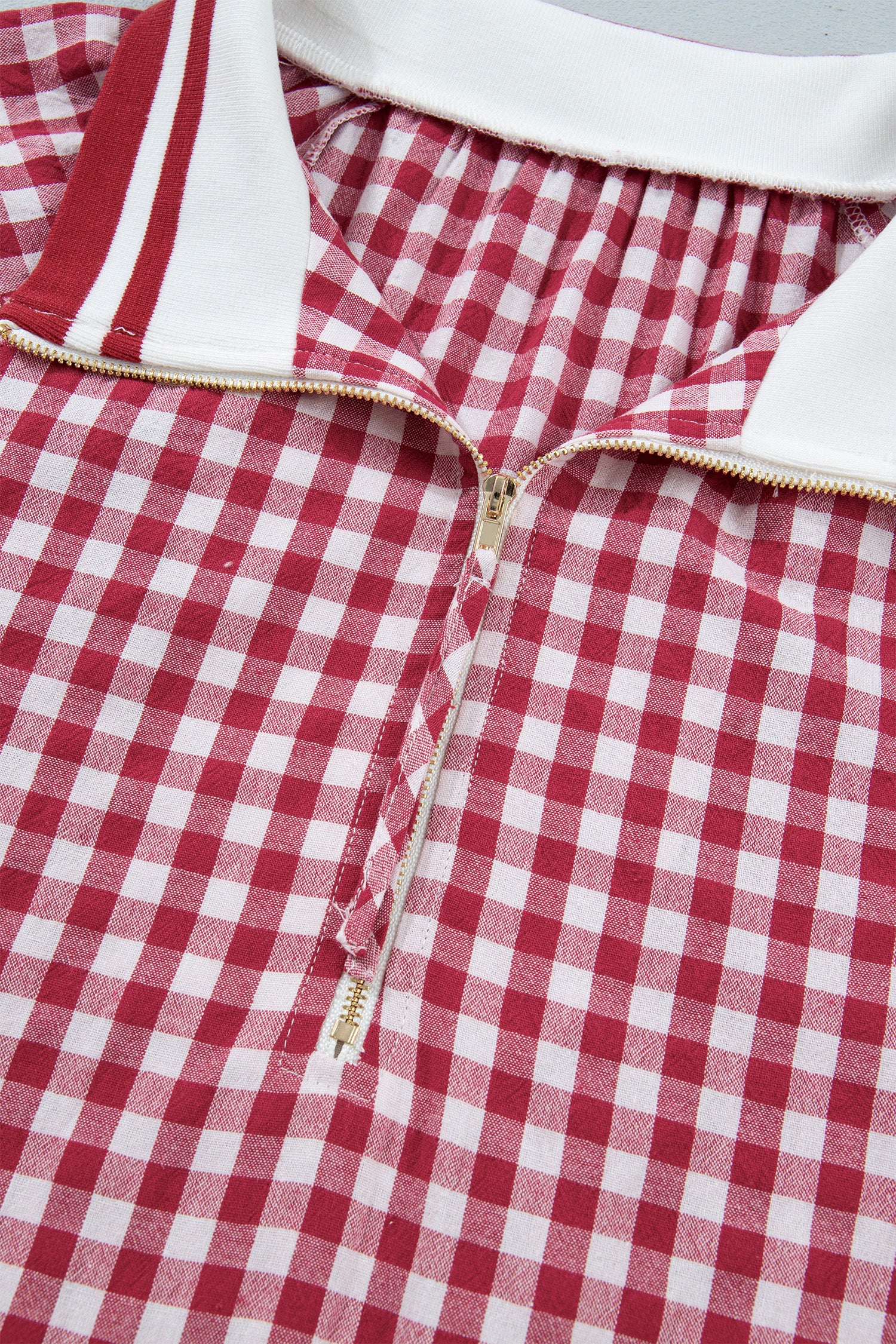 Detalhe da gola com fecho e padrão xadrez vermelho e branco da Red Gingham Striped Patchwork Half Zip Blouse, ideal para um estilo casual e confortável.