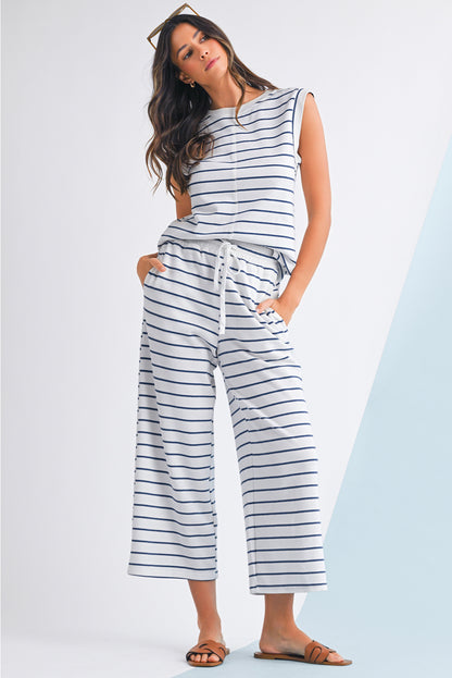 Mulher vestindo conjunto Sail Blue Casual Striped Tee and Wide Leg Pants Set, com camiseta sem mangas e calças largas listradas, em ambiente minimalista, promovendo estilo casual e conforto.