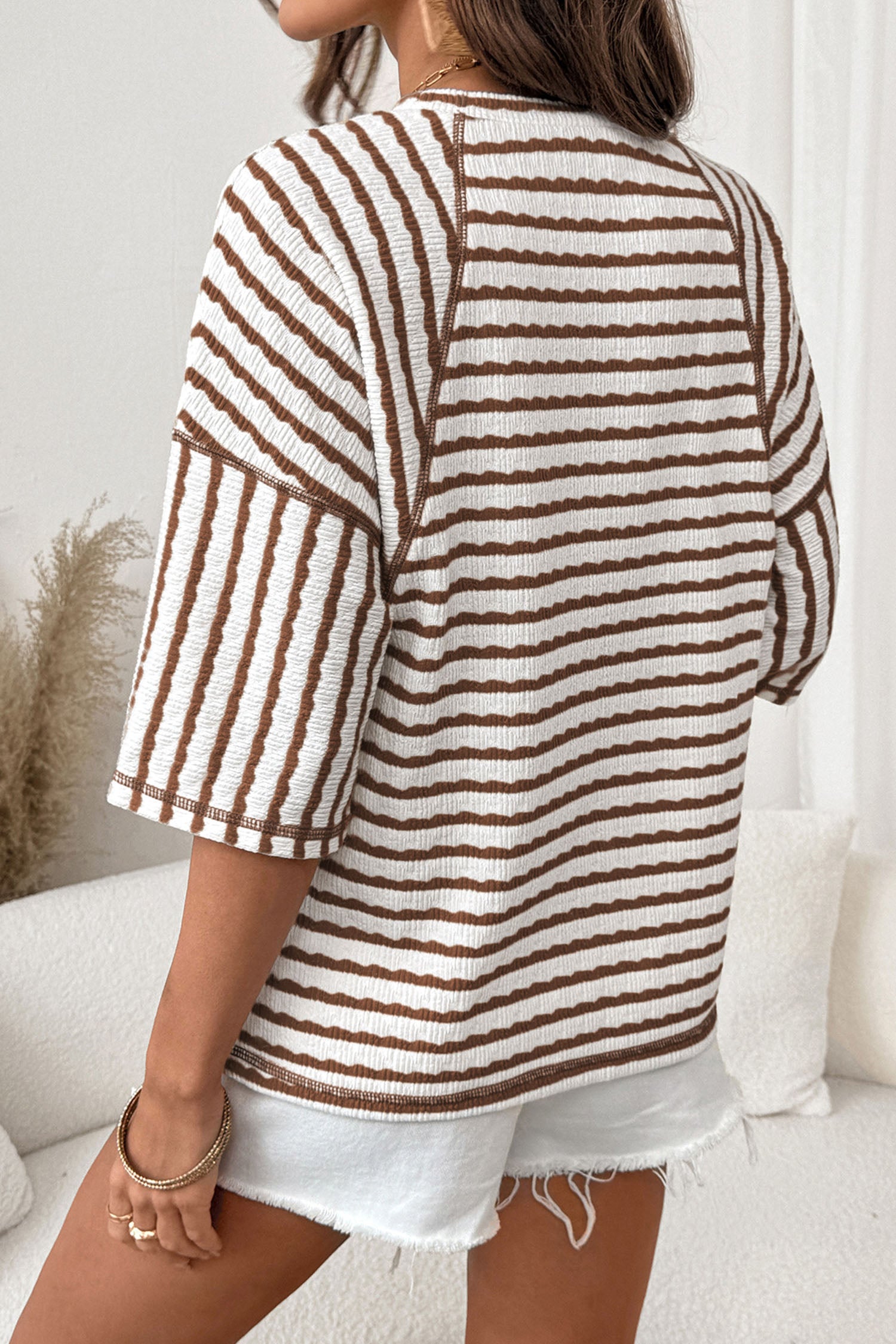 Mulher vestindo Apricot Stripe Textured Knit Split Hem Half Sleeve Loose Top, detalhe malha texturizada listrada em tons de branco e castanho, casual e confortável para o dia a dia.
