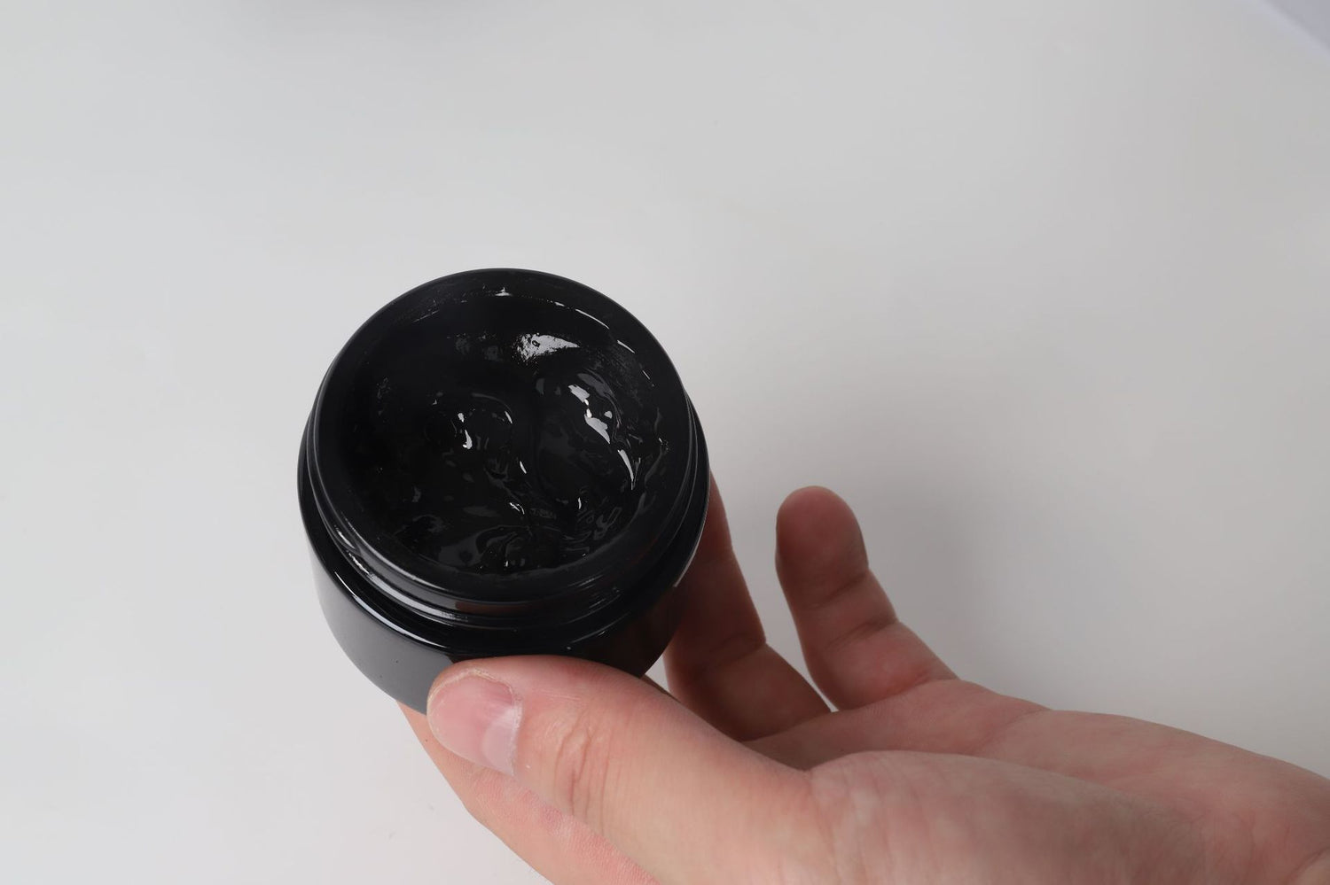 Mão segurando pote aberto de Pure Himalayan Shilajit SoftResin, suplemento premium natural em resina negra, usado para energia, vitalidade e saúde cognitiva no mercado português.