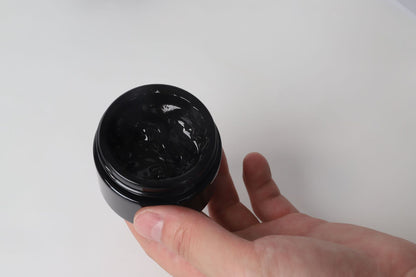 Mão segurando pote aberto de Pure Himalayan Shilajit SoftResin, suplemento premium natural em resina negra, usado para energia, vitalidade e saúde cognitiva no mercado português.