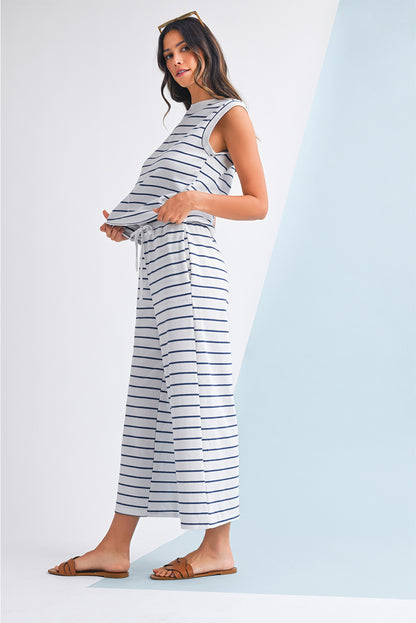 Mulher vestindo o conjunto Sail Blue Casual Striped Tee and Wide Leg Pants Set, composto por blusa sem mangas e calças largas de riscas azuis, num ambiente minimalista e sereno.