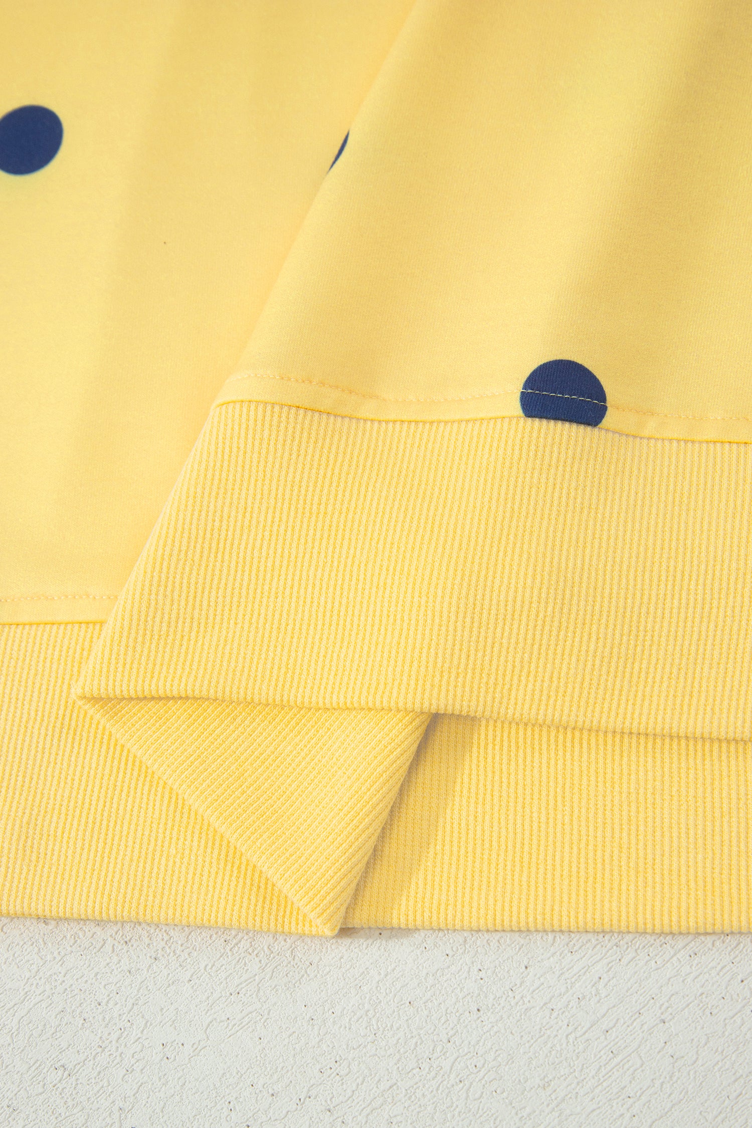 Detalhe do tecido amarelo com estampa de bolinhas azuis do Yellow Polka Dot Print Crossed Seam Detail Oversize Tee, destacando acabamento em malha canelada.