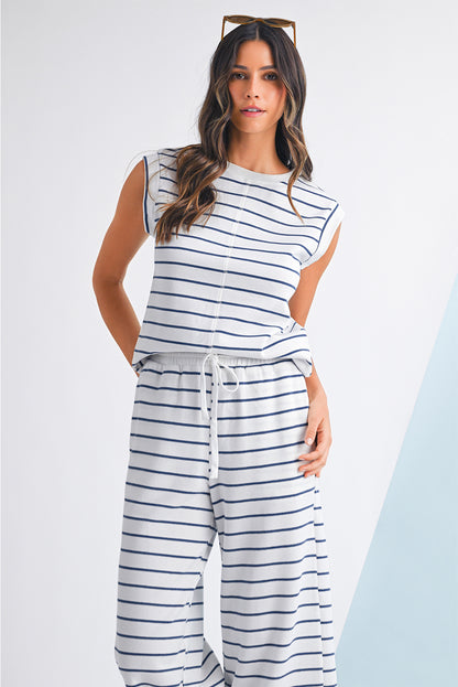 Mulher com cabelo ondulado usando o conjunto Sail Blue Casual Striped Tee and Wide Leg Pants Set branco com riscas azuis, em pose descontraída para promocionar suplementos premium naturais para energia, vitalidade e saúde cognitiva.