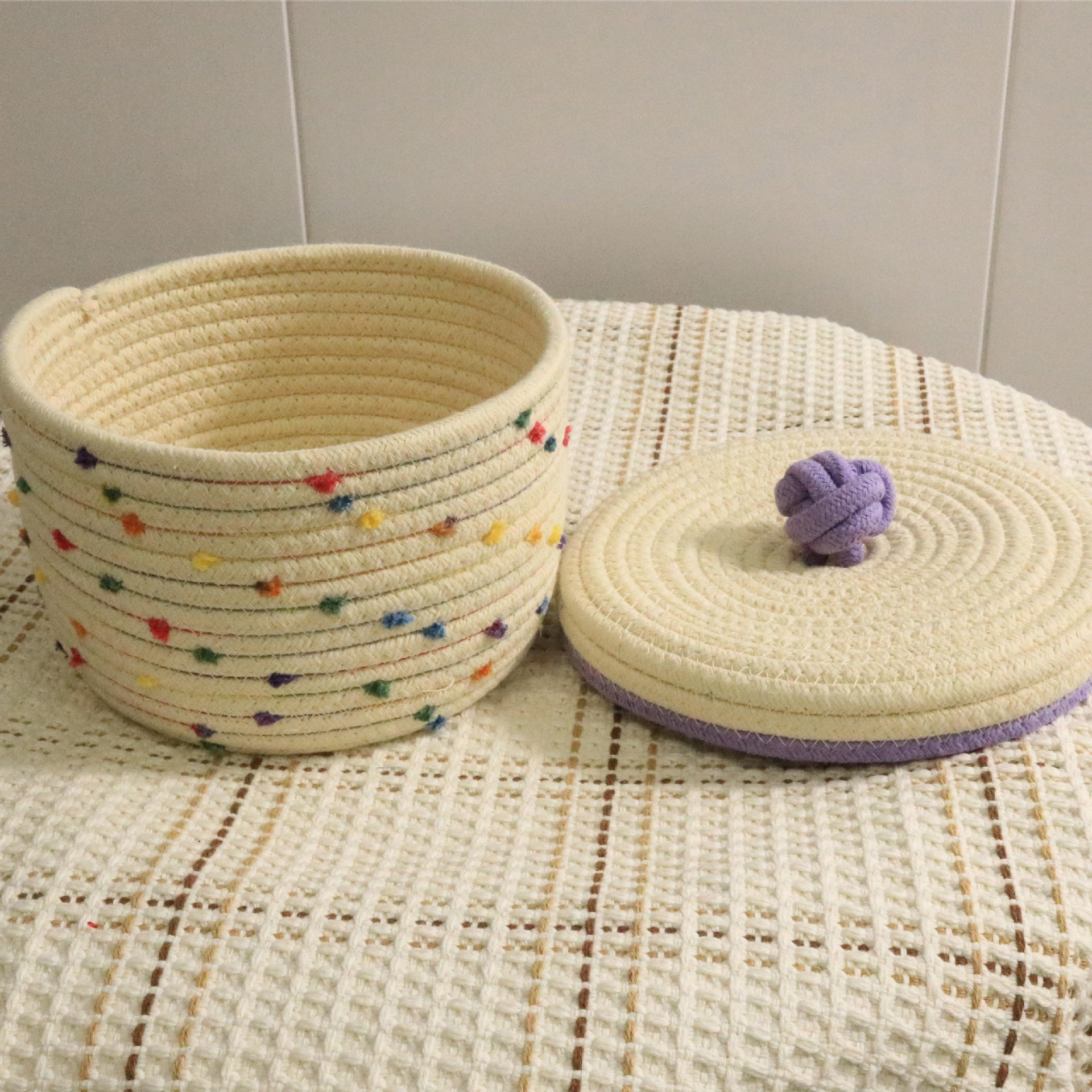 Creative desktop cosmetics storage woven basket em tom creme com pontos coloridos e tampa com detalhe em nó roxo, ideal para organizar suplementos premium naturais para energia, vitalidade e saúde cognitiva.