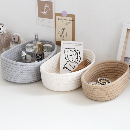 Arranjo de três storage box desktop miscellaneous items storage basket cosmetics snacks hallway hand woven cotton thread storage basket em tons cinza, branco e bege, organizando perfumes, cartões e acessórios, promovendo bem-estar natural e organização.