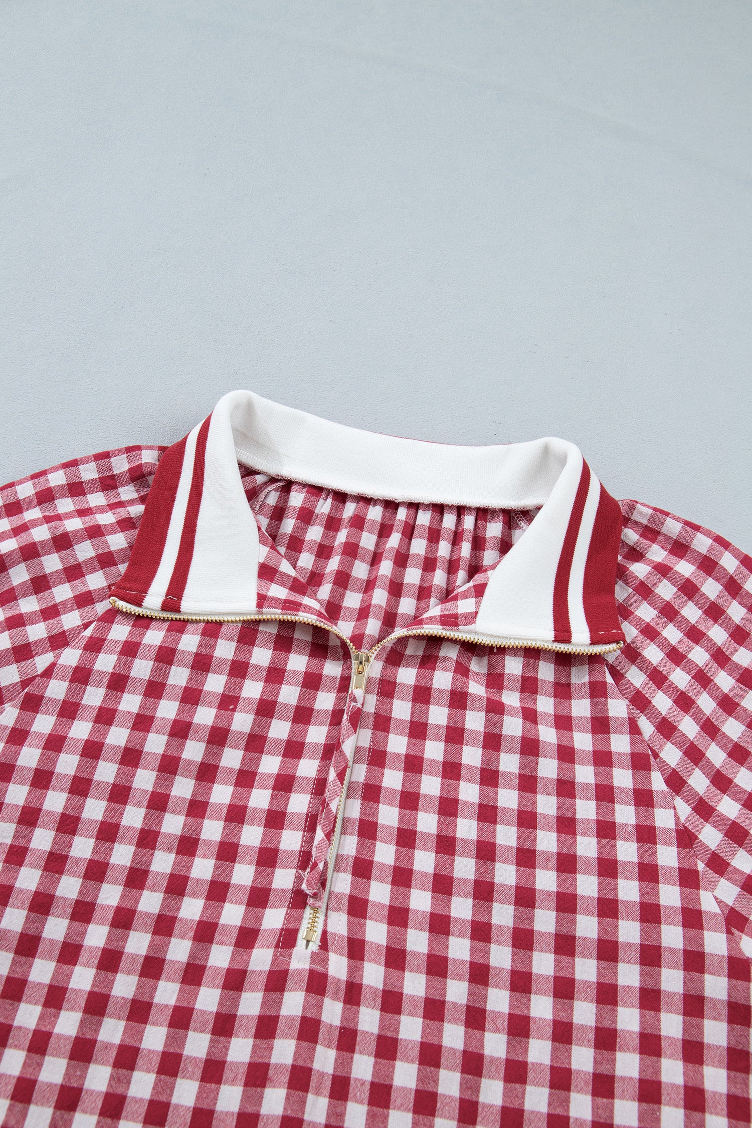 Blusa Red Gingham Striped Patchwork Half Zip Blouse com padrão xadrez vermelho e branco, gola com fecho meia-zíper, ideal para complementar looks casuais com energia e vitalidade.