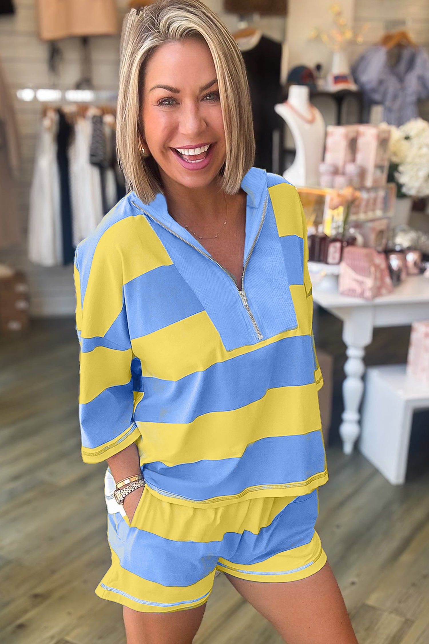 Mulher sorridente vestindo Pink Seam Detail Half Zip Tee Casual Shorts 2pcs Set listrado azul e amarelo, em loja moderna, transmitindo bem-estar natural e vitalidade.