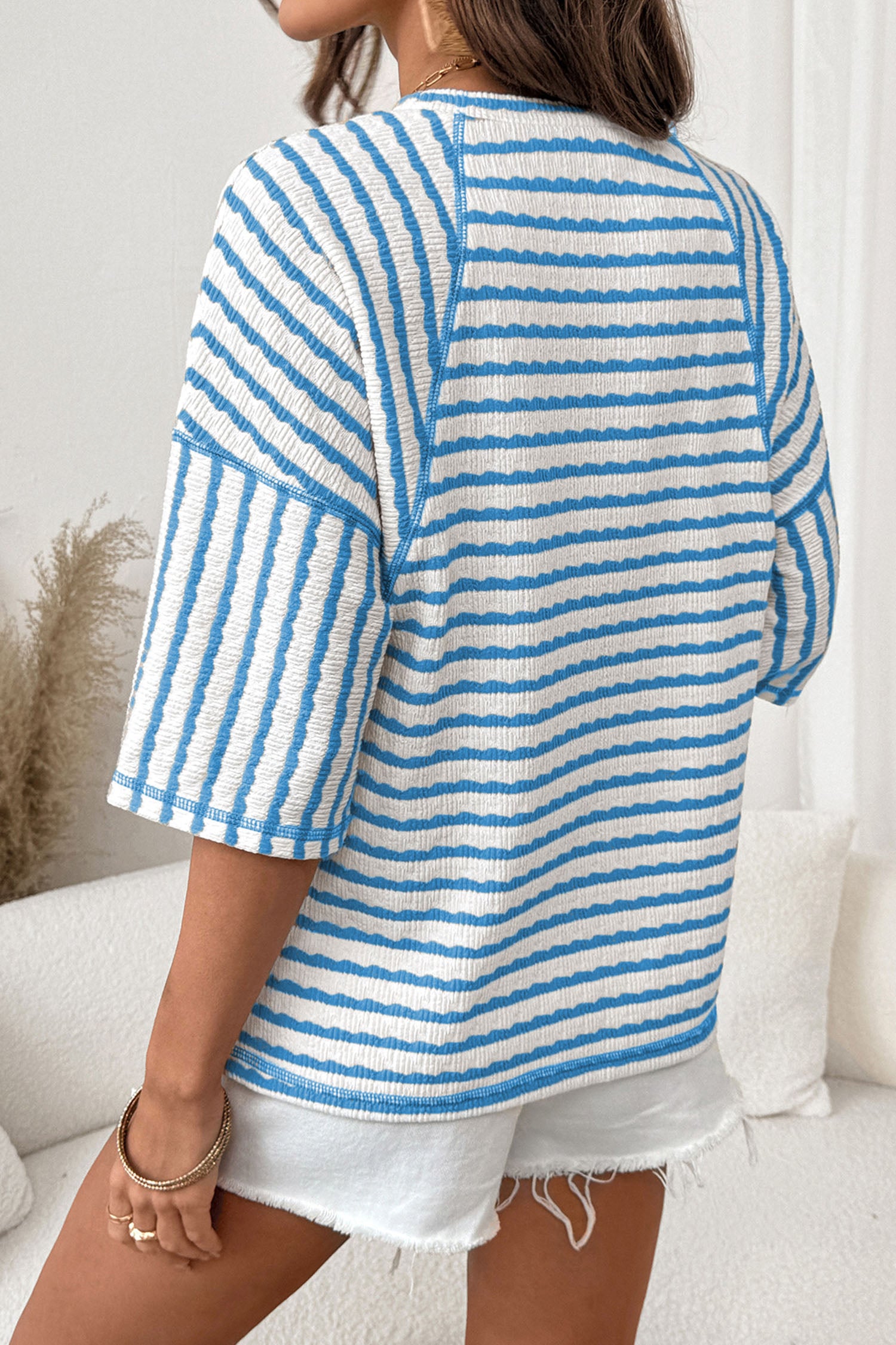 Mulher vestindo Apricot Stripe Textured Knit Split Hem Half Sleeve Loose Top azul e branco, peça solta com malha texturizada, destacando conforto e estilo casual para suplementos premium naturais para energia, vitalidade e saúde cognitiva, desenvolvidos para o mercado português.