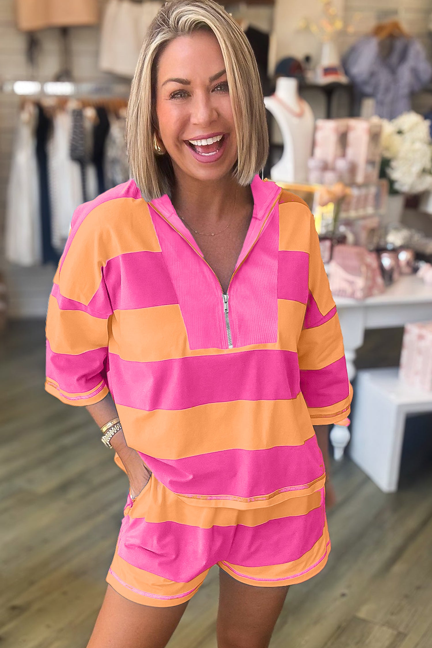 Mulher sorrindo usando conjunto casual Pink Seam Detail Half Zip Tee Casual Shorts 2pcs Set com riscas largas cor-de-rosa e laranja, promovendo suplementos premium naturais para energia, vitalidade e saúde cognitiva.