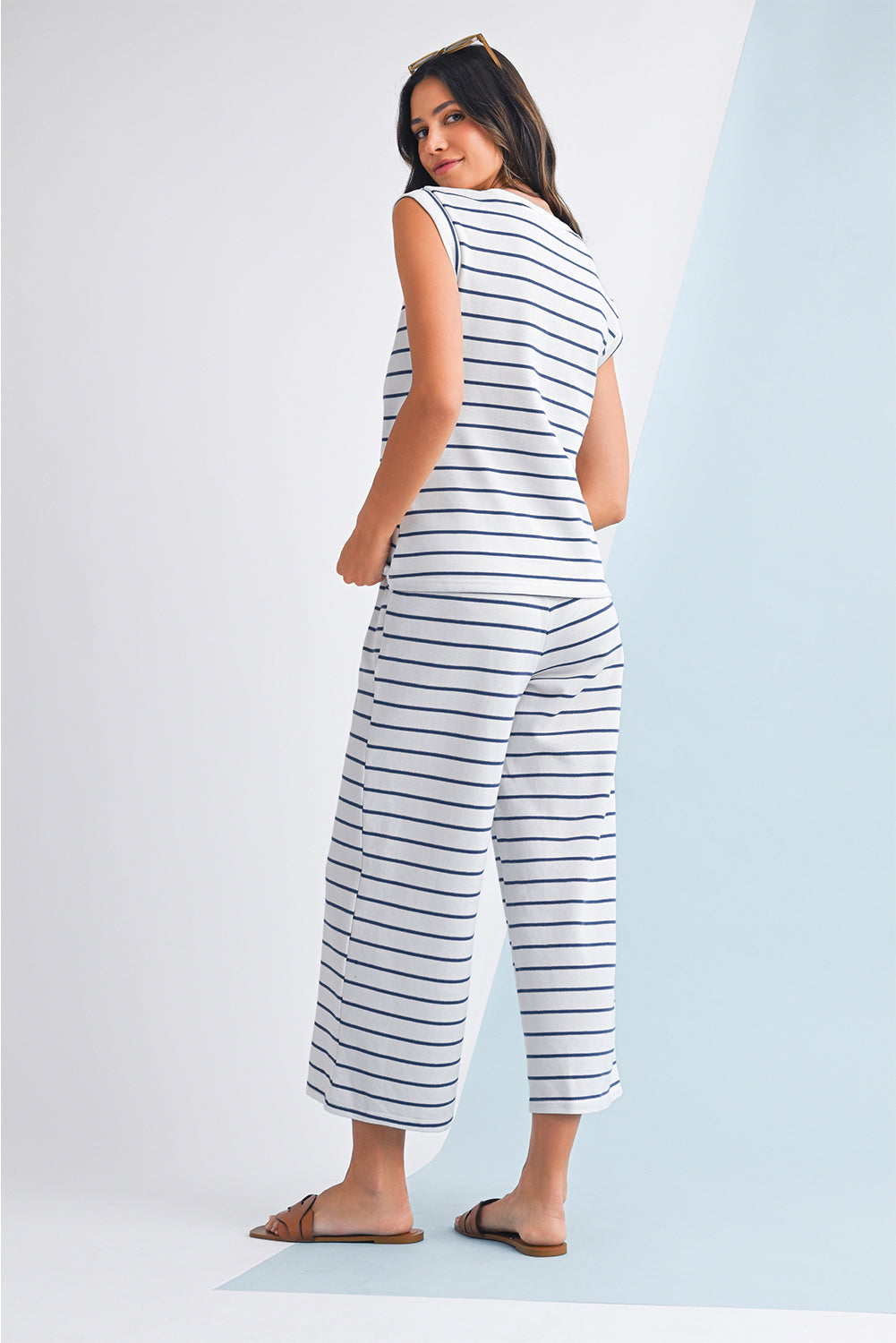 Mulher de costas vestindo Sail Blue Casual Striped Tee and Wide Leg Pants Set branco com riscas azuis, casual, em ambiente claro, transmitindo estilo e conforto.