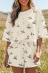 Mulher sorridente usando Beige Mallard Duck Print Oversized Tee Drawstring Short Set em tom bege com estampa de patos, transmitindo conforto e estilo natural ao ar livre.