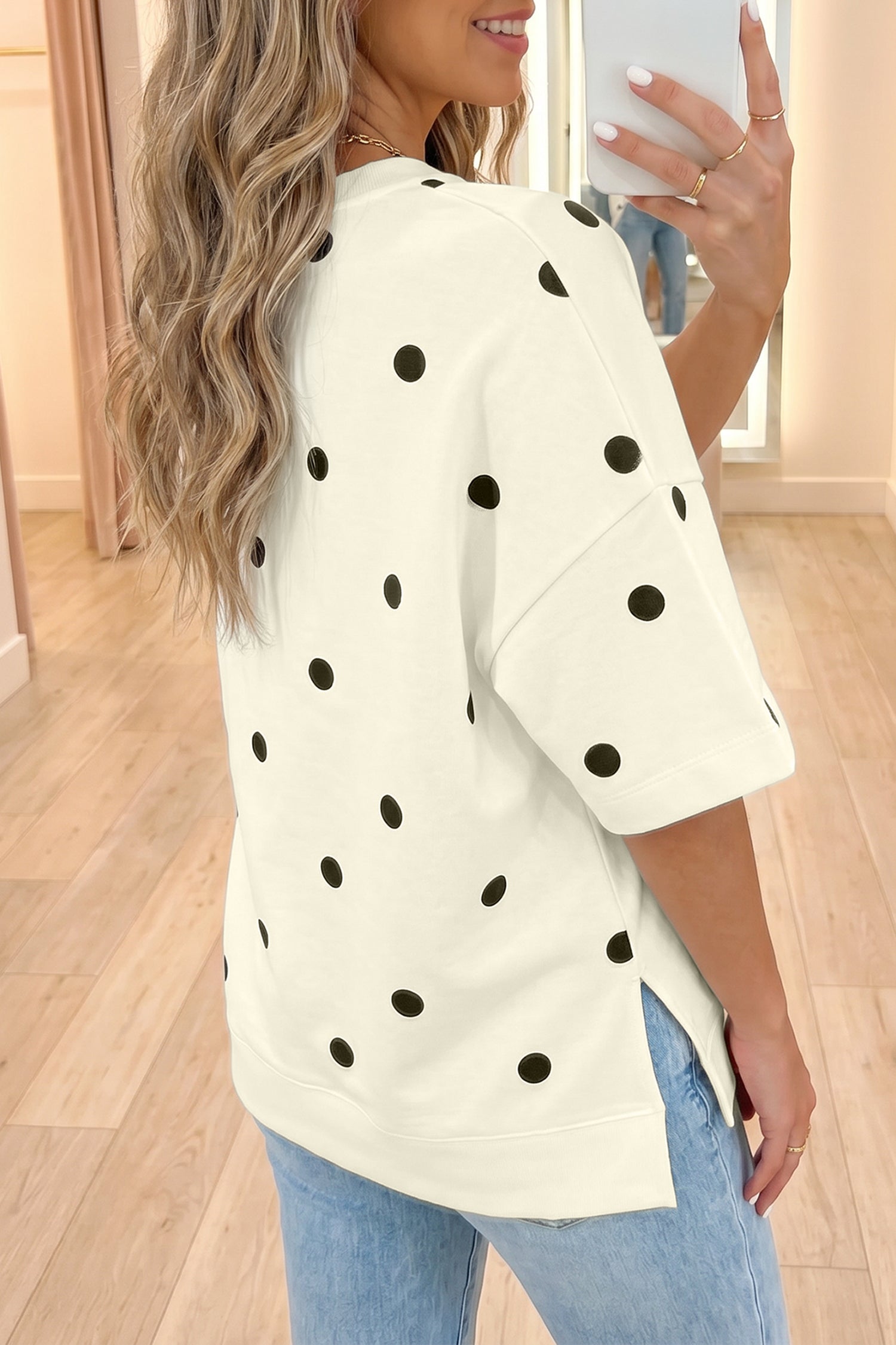 Mulher de cabelo loiro ondulado veste Yellow Polka Dot Print Crossed Seam Detail Oversize Tee branca com bolinhas pretas, combinando estilo casual e conforto natural.