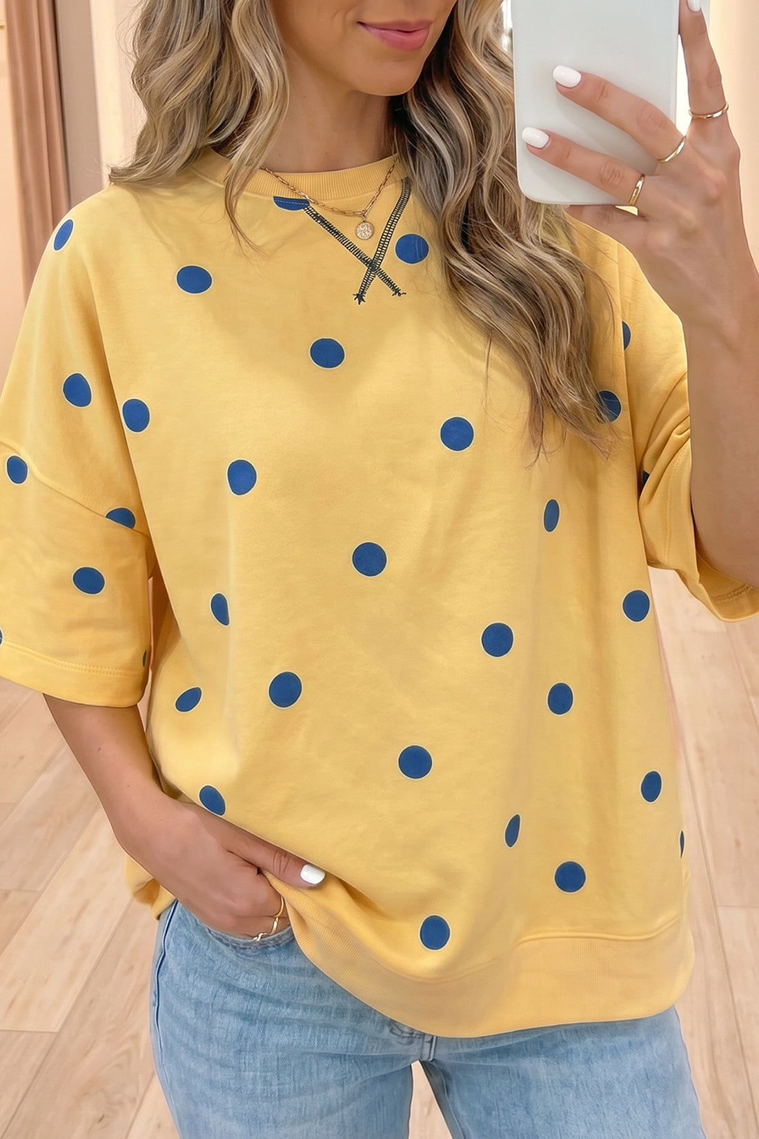 Mulher com Yellow Polka Dot Print Crossed Seam Detail Oversize Tee amarela com bolinhas azuis, cabelo ondulado, usando colares delicados, estilo casual elegante para complementar suplementos premium naturais para energia, vitalidade e saúde cognitiva.