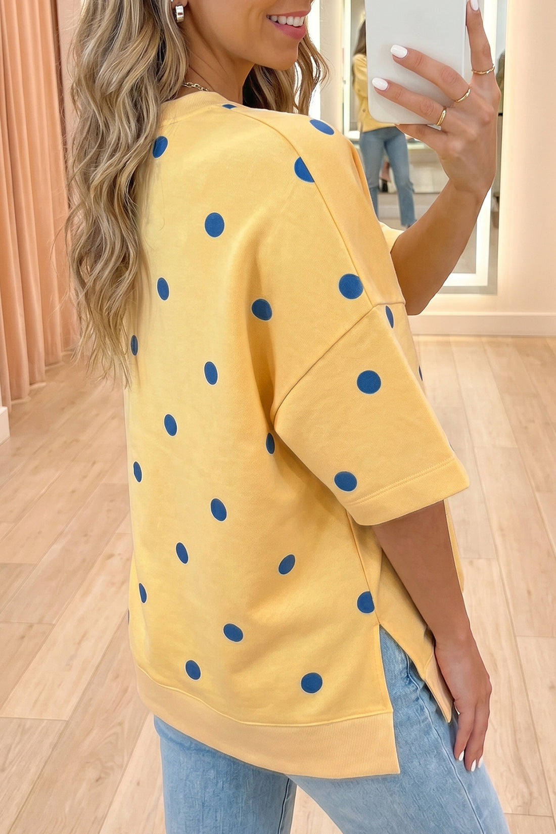 Mulher a tirar selfie vestindo Yellow Polka Dot Print Crossed Seam Detail Oversize Tee amarelo com bolinhas azuis, destacando o tecido confortável e estilo casual, complementando suplementos premium naturais para energia, vitalidade e saúde cognitiva, desenvolvidos para o mercado português.