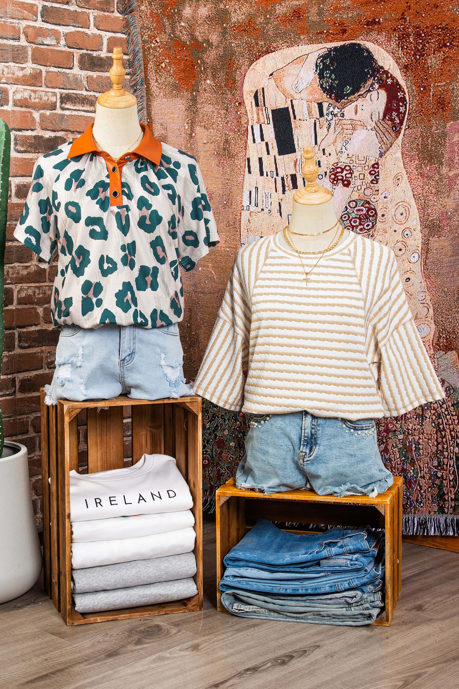 Mannequins vestindo uma Apricot Stripe Textured Knit Split Hem Half Sleeve Loose Top listrada bege com branco e um polo animal print com gola laranja, em ambiente decorado com quadros e roupas dobradas, destacando suplementos premium naturais para energia, vitalidade e saúde cognitiva desenvolvidos para o mercado português.