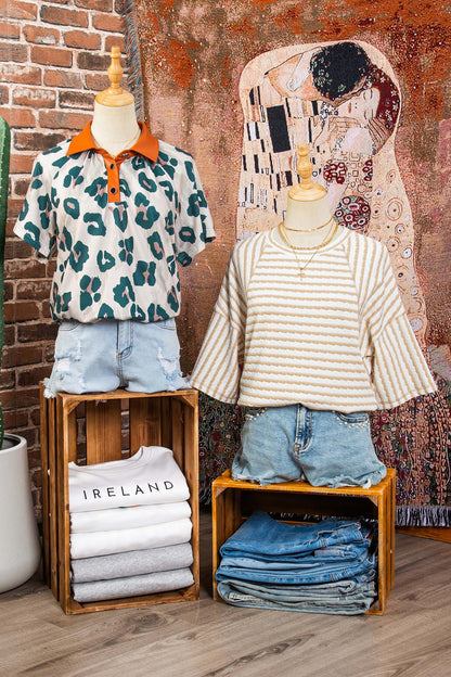 Mannequins vestindo uma Apricot Stripe Textured Knit Split Hem Half Sleeve Loose Top listrada bege com branco e um polo animal print com gola laranja, em ambiente decorado com quadros e roupas dobradas, destacando suplementos premium naturais para energia, vitalidade e saúde cognitiva desenvolvidos para o mercado português.