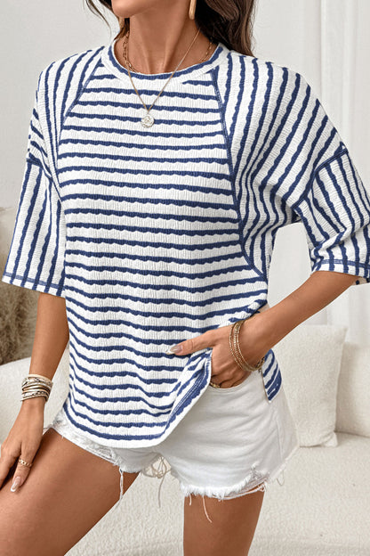 Mulher vestindo Apricot Stripe Textured Knit Split Hem Half Sleeve Loose Top listrada azul-marinho e branca, combinada com shorts brancos, destacando estilo casual e conforto para uso diário.